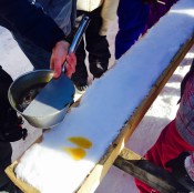 Hot maple syrup taffy is being placed on clean snow